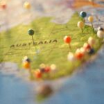 Australia show on a paper map with colorful pins marking places on it.