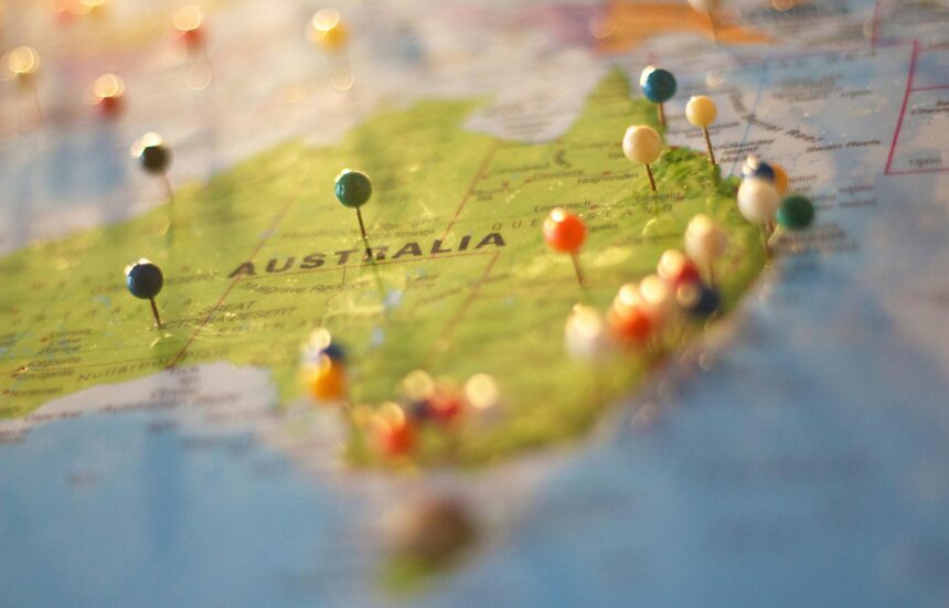 Australia show on a paper map with colorful pins marking places on it.