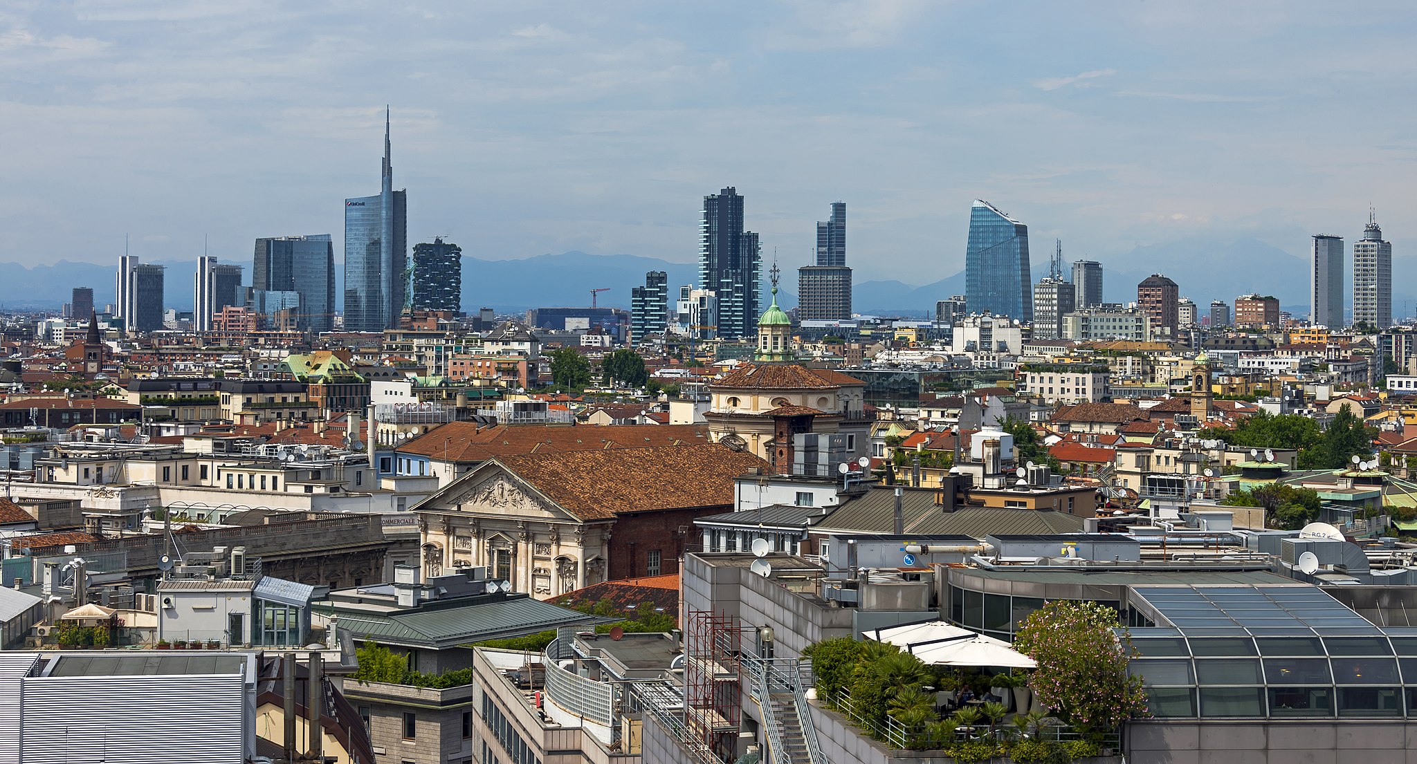 The entire Milan, Italy skyline from the Cathedral roof, with the old town surrounded by apartment buildings and high-rise offices in the distance.
