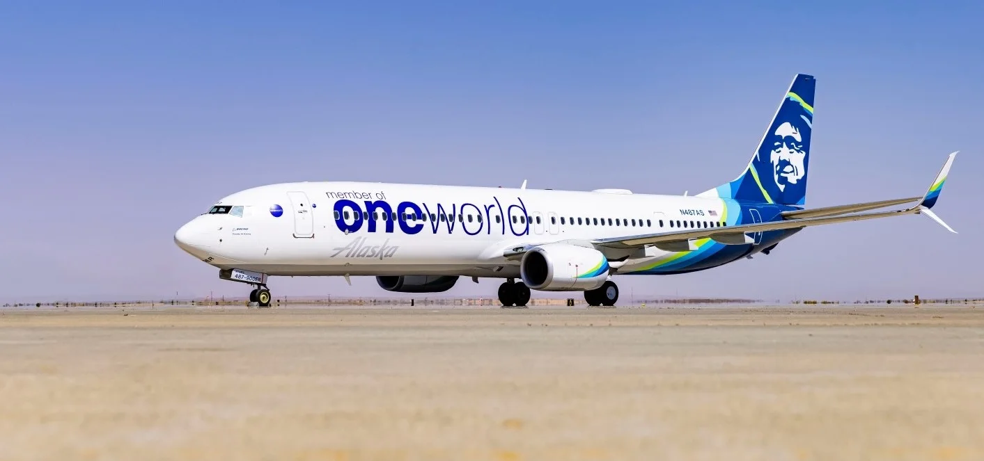 A oneworld-Alaska aircraft on the ground, blue sky in the background.