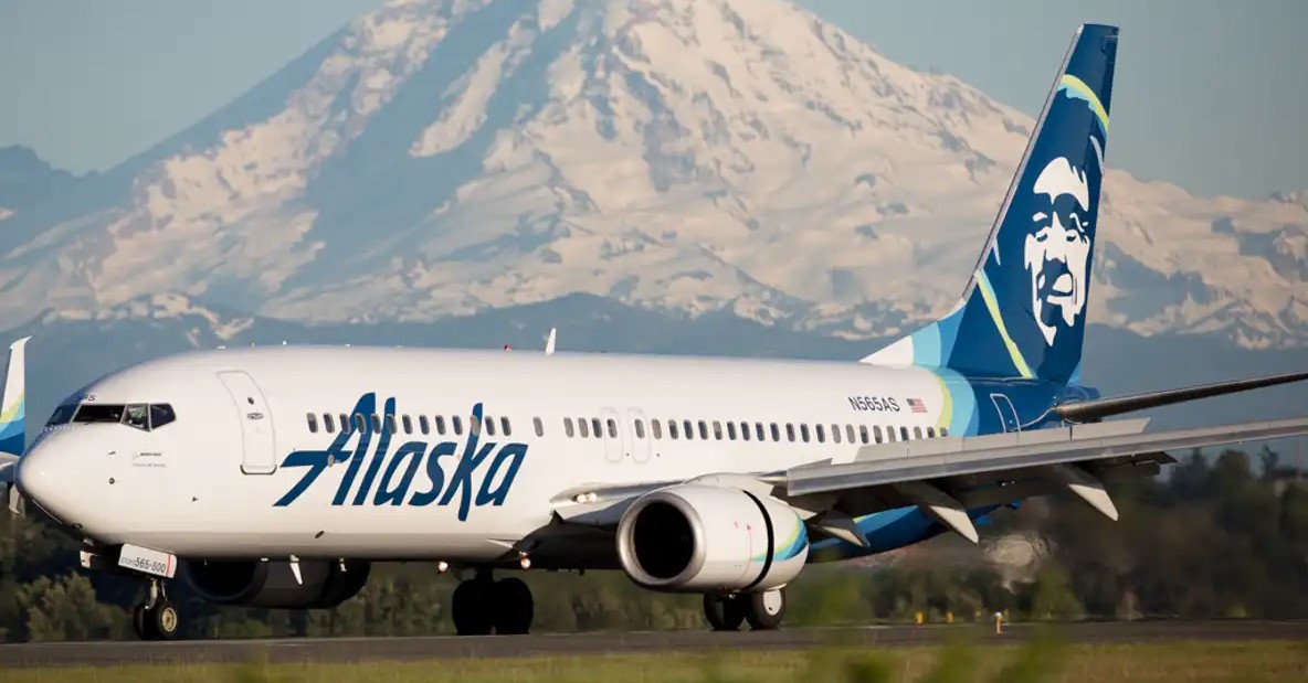 Alaska aircraft in the foreground, snowy mountain in the background.