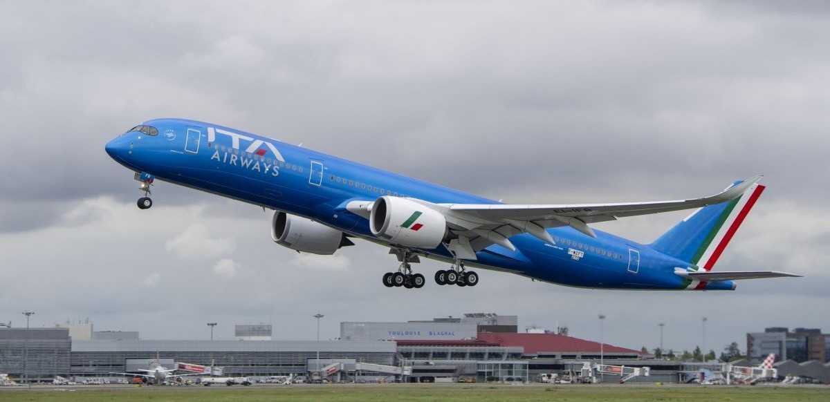ITA Airways Airbus A350-900 aircraft taking flight, grey clouds in the background.