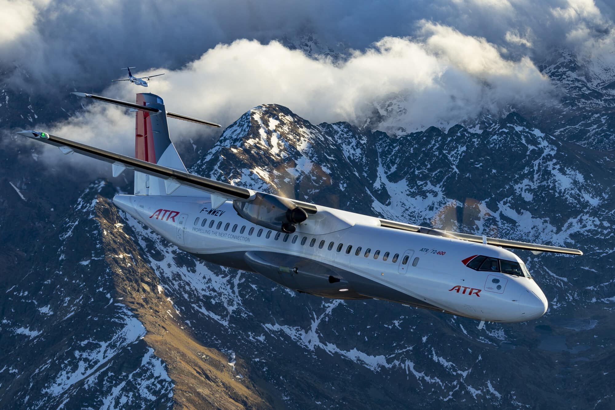 SUM Air ATR aircraft flying with mountain range in the background.