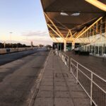 Side view of London Stansted Airport exterior, railings in front of the building, blue sky in background.