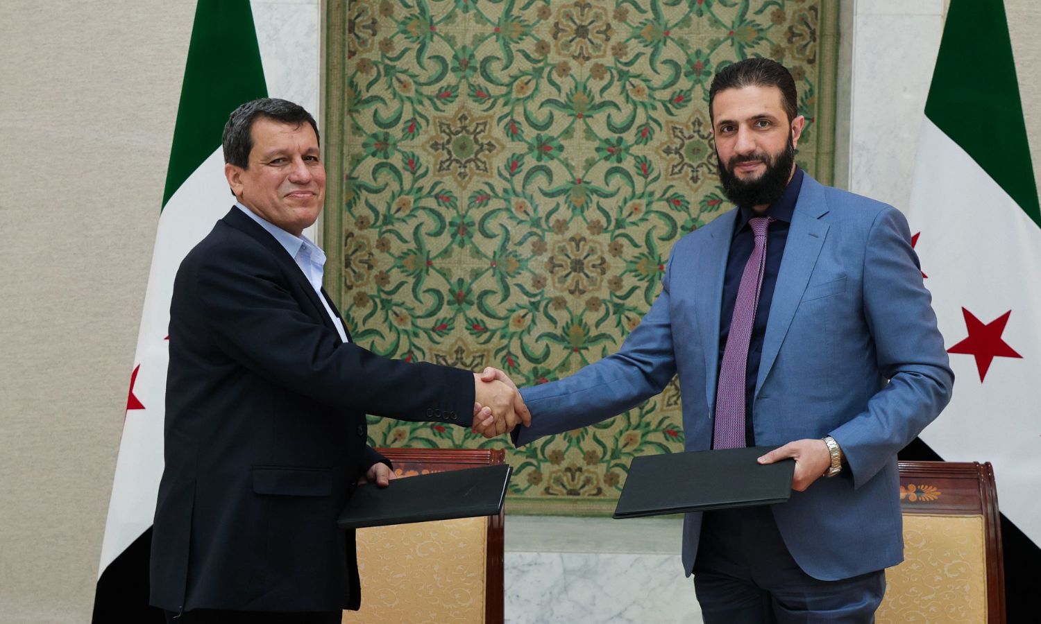 Interim Syrian president Ahmed al-Sharaa, right, shakes hands with Mazloum Abdi of SDF, left, in Damascus.