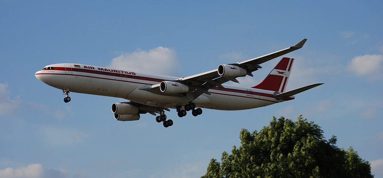 Air Mauritius aircraft flying overhead in the blue sky.