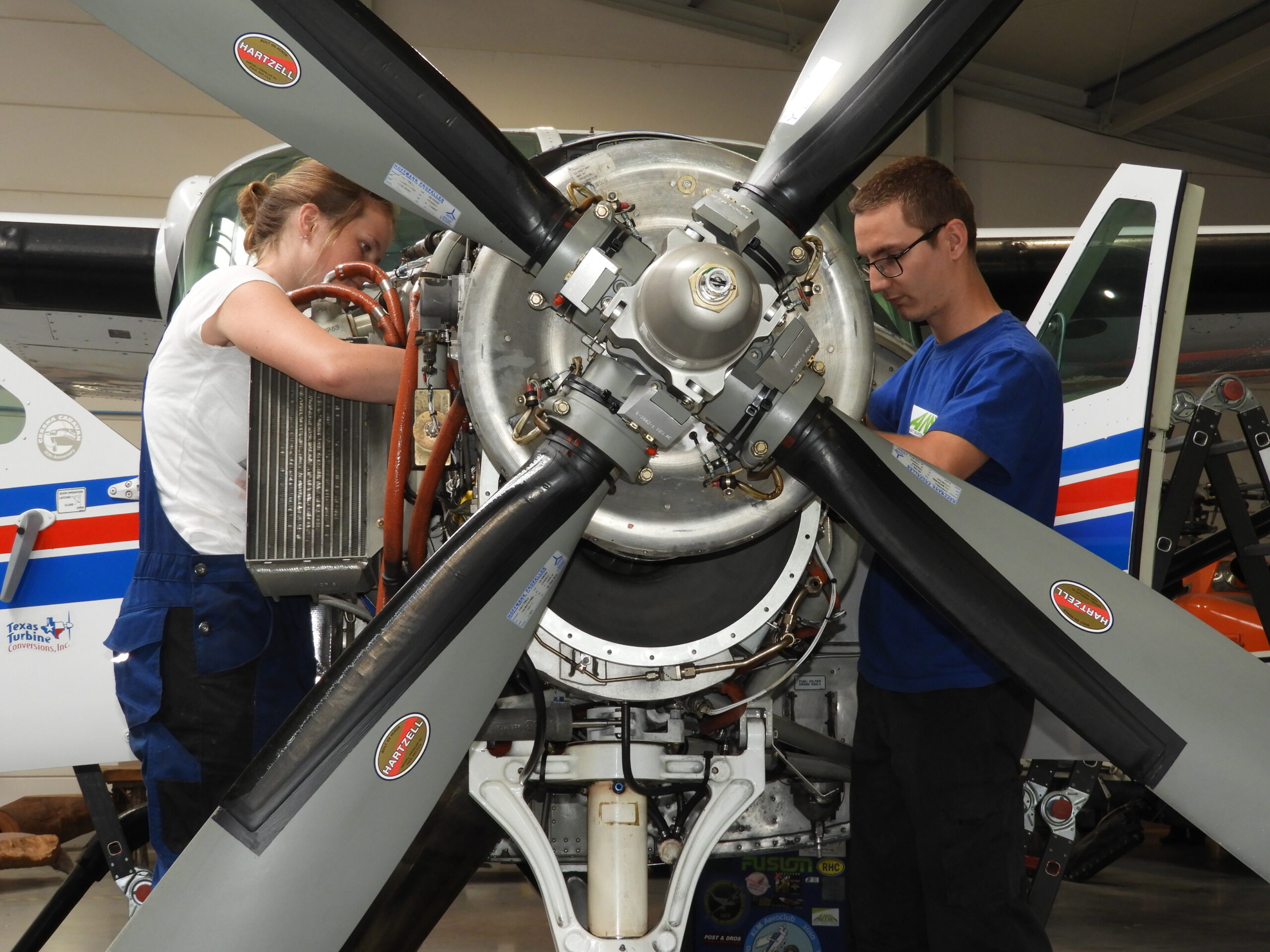 Two people do maintenance work on a small turboprop.