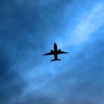 Silhouette of a commercial aircraft flying through a dark blue sky, illustrating airline geopolitical risk, flight suspensions and airspace closures as airlines avoid conflict zones.