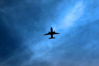 Silhouette of a commercial aircraft flying through a dark blue sky, illustrating airline geopolitical risk, flight suspensions and airspace closures as airlines avoid conflict zones.