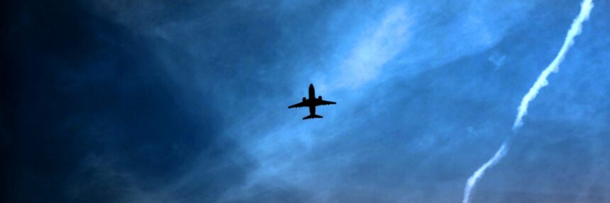 Silhouette of a commercial aircraft flying through a dark blue sky, illustrating airline geopolitical risk, flight suspensions and airspace closures as airlines avoid conflict zones.