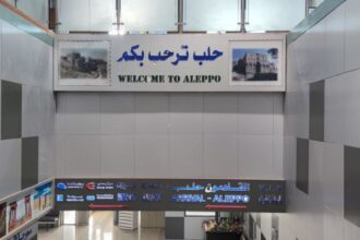 Arrivals area at Aleppo Airport, with signage written in English and Arabic.