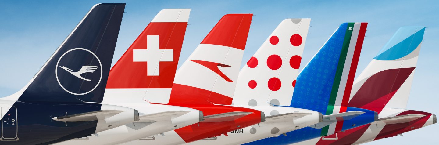 Aircraft tails from multiple Lufthansa Group airlines are lined up, showing different logos and color schemes that constitute the partnership.