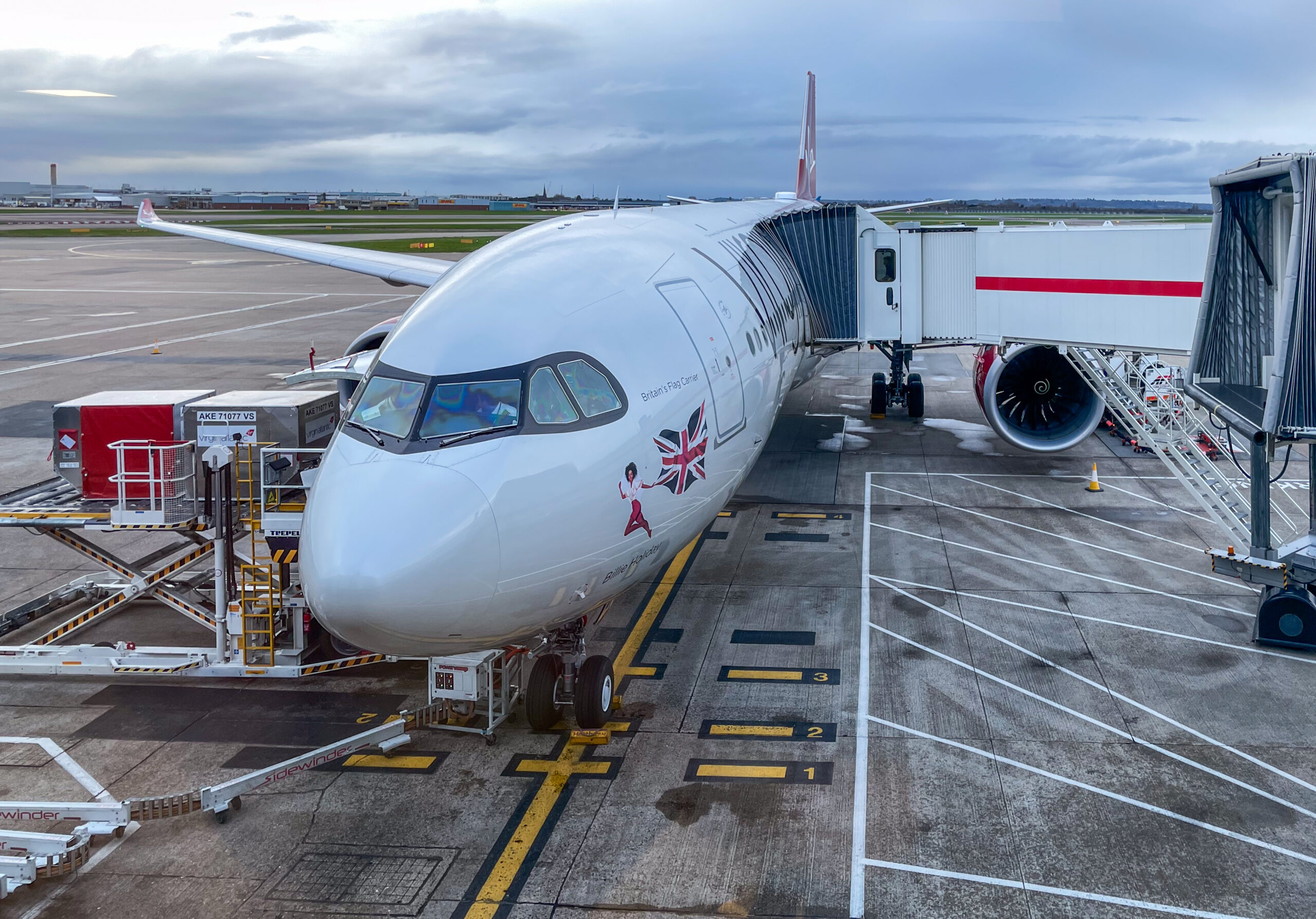 Airbus A330 (G-VJAZ) of Virgin Atlantic on the tarmac and connected to a boarding gate at London Heathrow Airport.