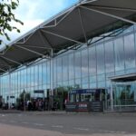 Bristol Airport terminal building, arrivals, with some people by the door.