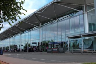 Bristol Airport terminal building, arrivals, with some people by the door.