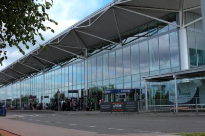 Bristol Airport terminal building, arrivals, with some people by the door.