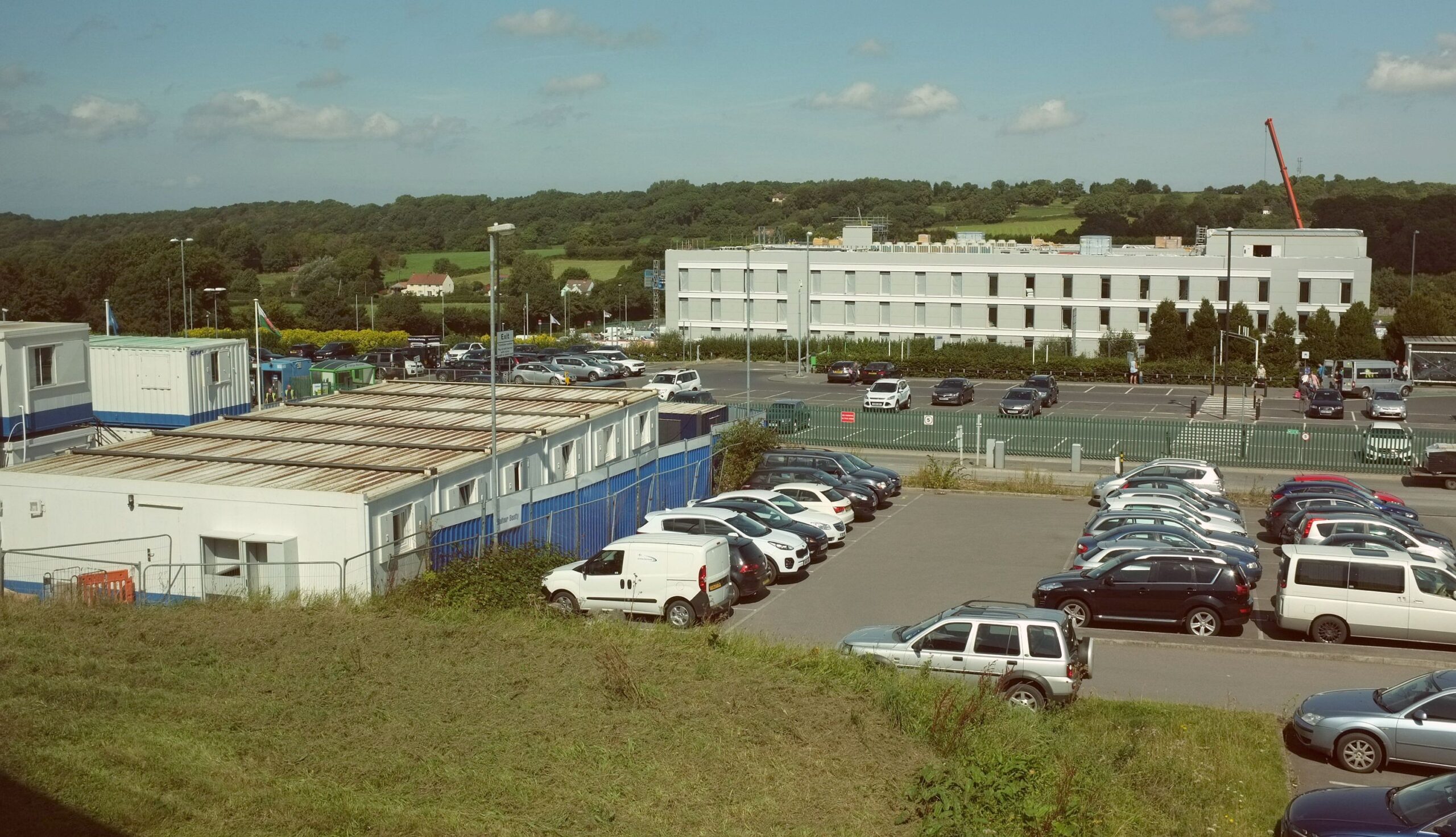 Several cars are parked outdoors, close to the airport buildings.