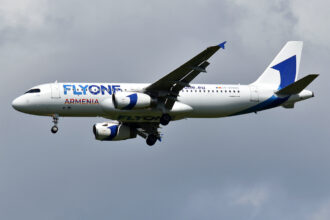 A320 by FlyOne Armenia flies with clouds in the background.