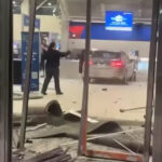 A black Mercedes sedan crashed inside Detroit Metro Airport's terminal, surrounded by debris from a shattered ticket counter.