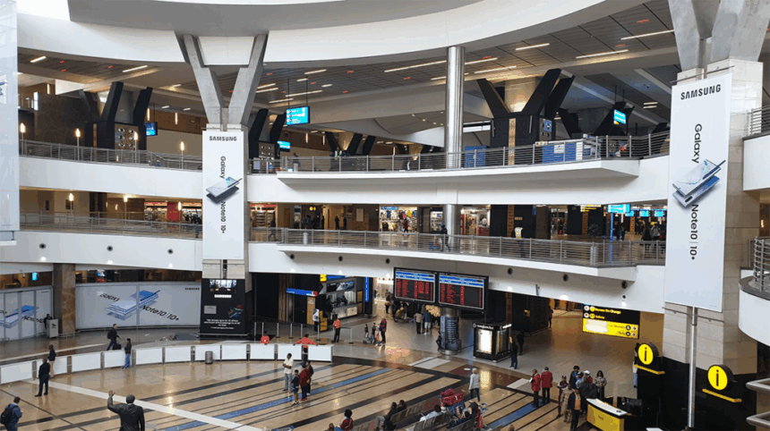 Interior of O.R. Tambo International Airport in Johannesburg, showing a spacious terminal with high ceilings and travelers moving through the concourse.