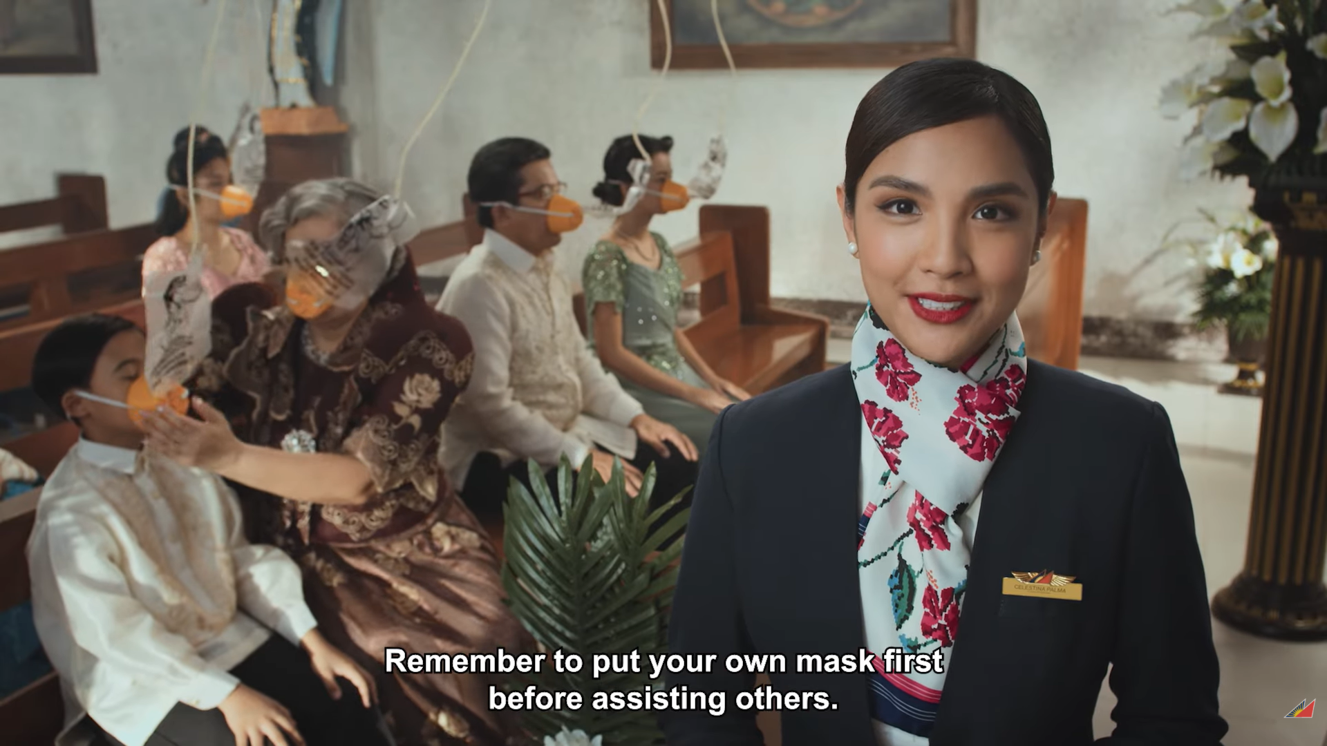 A family sitting in a church puts on oxygen masks. A flight attendant speaks on the foreground.