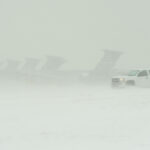 Several aircraft and a truck during a heavy snowstorm.