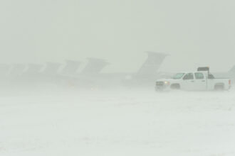 Several aircraft and a truck during a heavy snowstorm.
