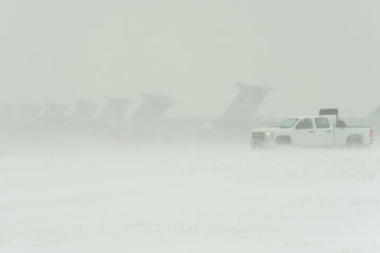 Several aircraft and a truck during a heavy snowstorm.