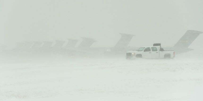 Several aircraft and a truck during a heavy snowstorm.
