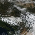 Satellite image of snow-covered regions in British Columbia and Alberta illustrating severe winter weather, linked to Canada flight disruptions, flight delays Canada, and flight cancellations Canada.