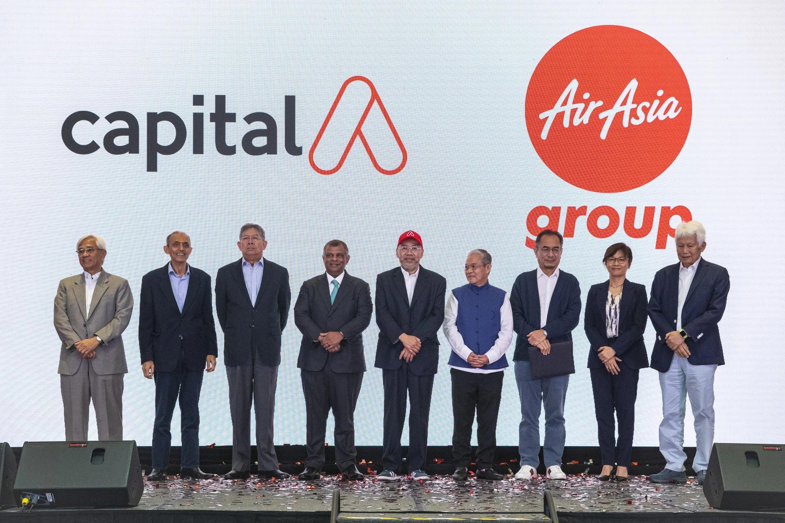 Stakeholders and executives of AirAsia and Capital A pose in front of their company logos at a conference