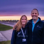 Shona Bowman (Former Aerobility Chairman) hugs Neil Tucker, newly appointed Aerobility Chair at Blackbushe Airport, at sunset.