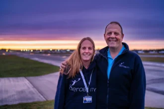Shona Bowman (Former Aerobility Chairman) hugs Neil Tucker, newly appointed Aerobility Chair at Blackbushe Airport, at sunset.