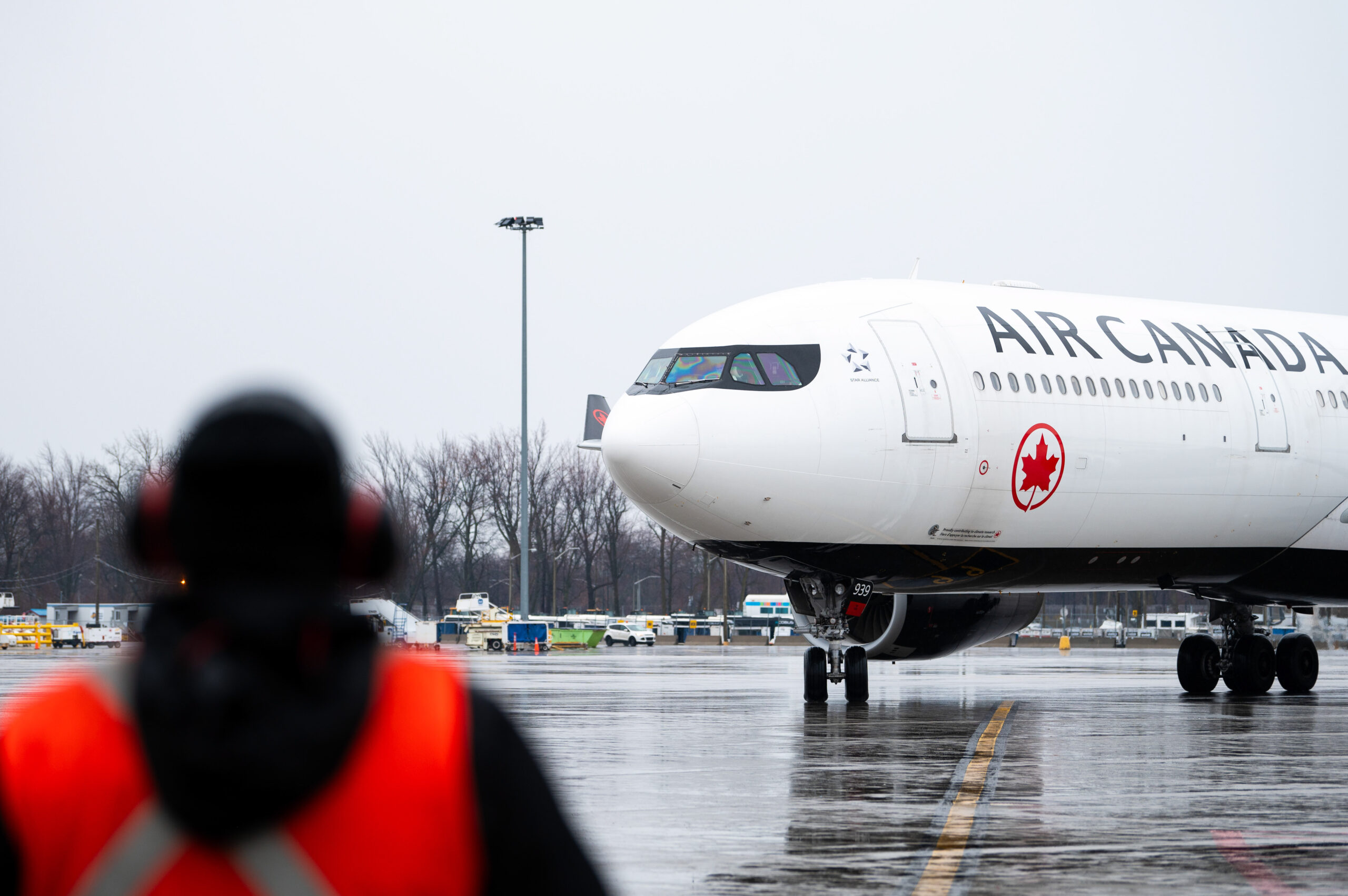 An image of an Air Canada employee guiding an Air Canada Airbus A330-8 Aircraft