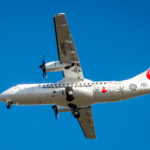 ATR aircraft flying in the blue sky, the under side of the aircraft showing.