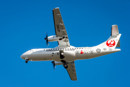 ATR aircraft flying in the blue sky, the under side of the aircraft showing.