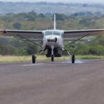 A Cessna 208 Grand Caravan touching down on a flat stretch of land.
