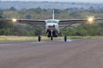 A Cessna 208 Grand Caravan touching down on a flat stretch of land.