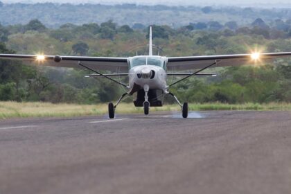 A Cessna 208 Grand Caravan touching down on a flat stretch of land.