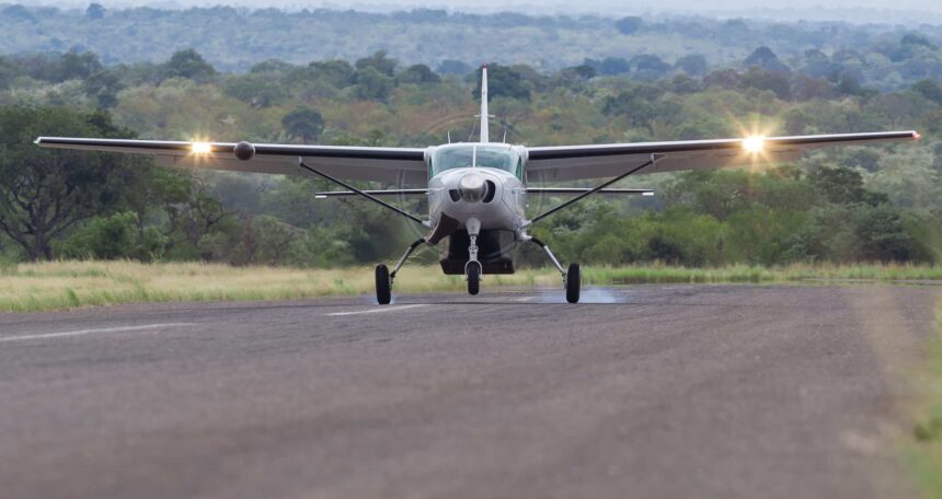A Cessna 208 Grand Caravan touching down on a flat stretch of land.