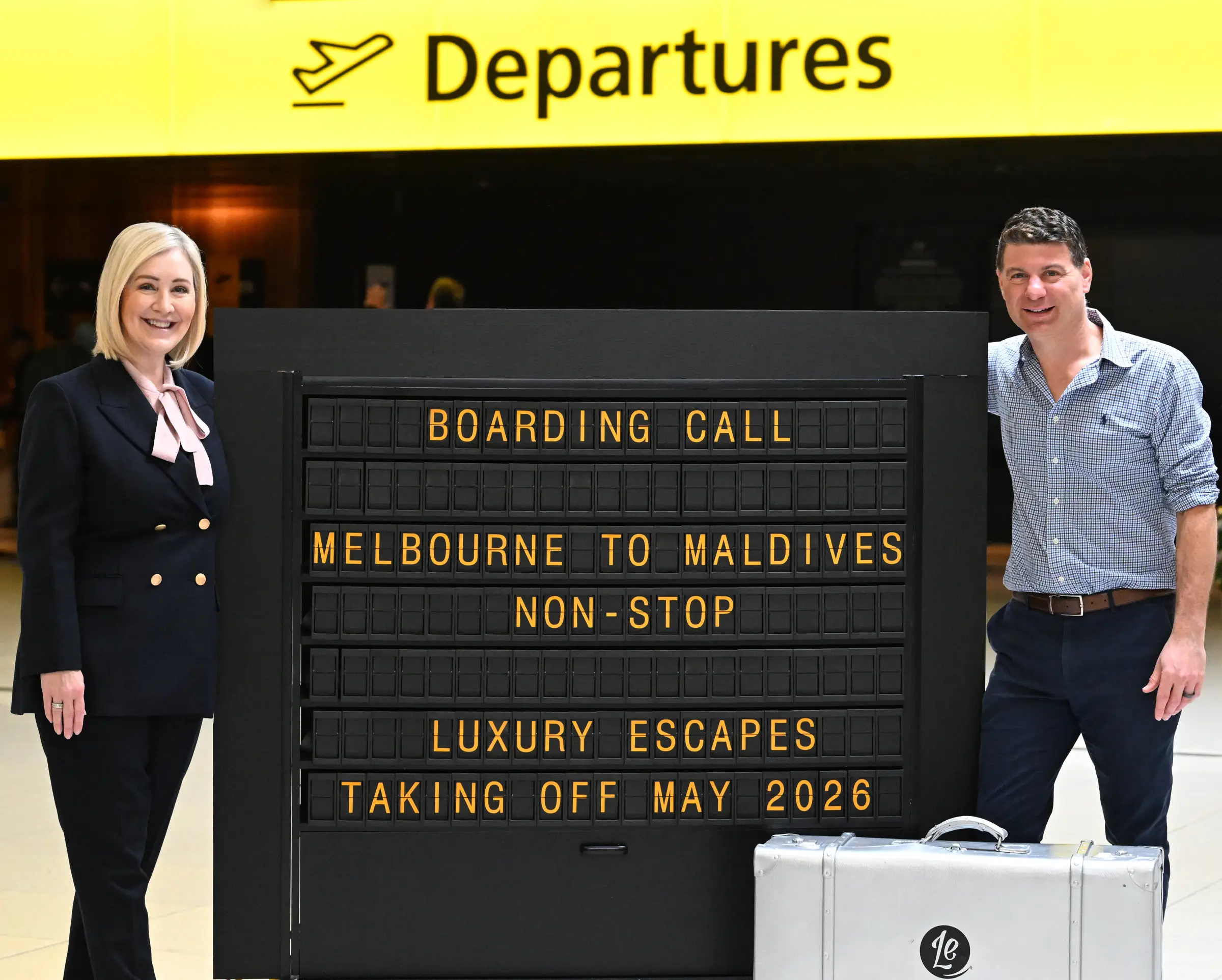 Man and woman standing next to a Flight Information Display System (FIDS)