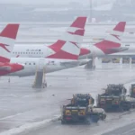 Planes parked on icy runways at Vienna International Airport, operations halted as thick ice repeatedly refreezes despite clearing efforts.