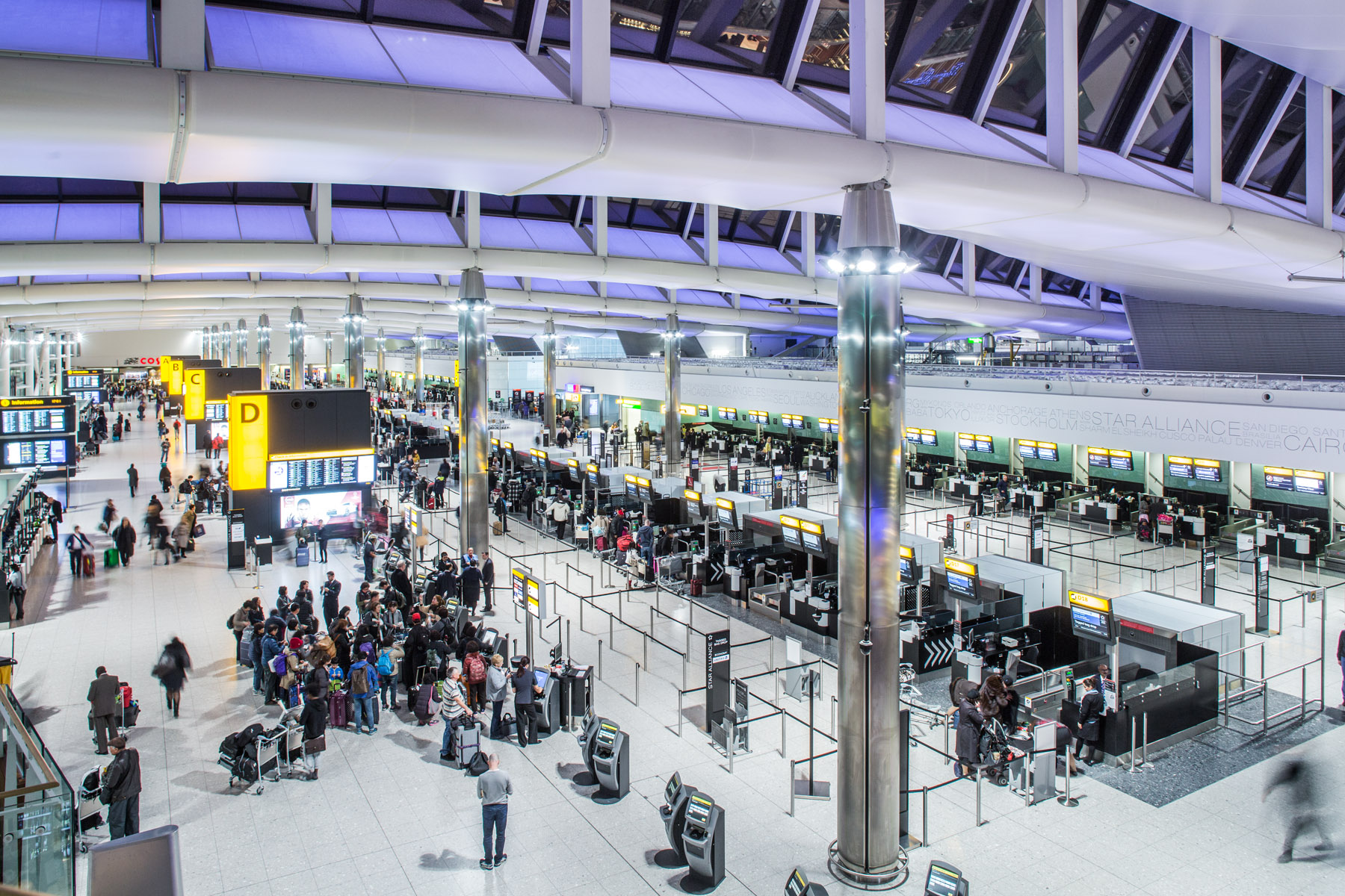 Image shows Terminal check-in hall from above with passengers visible and bright lights