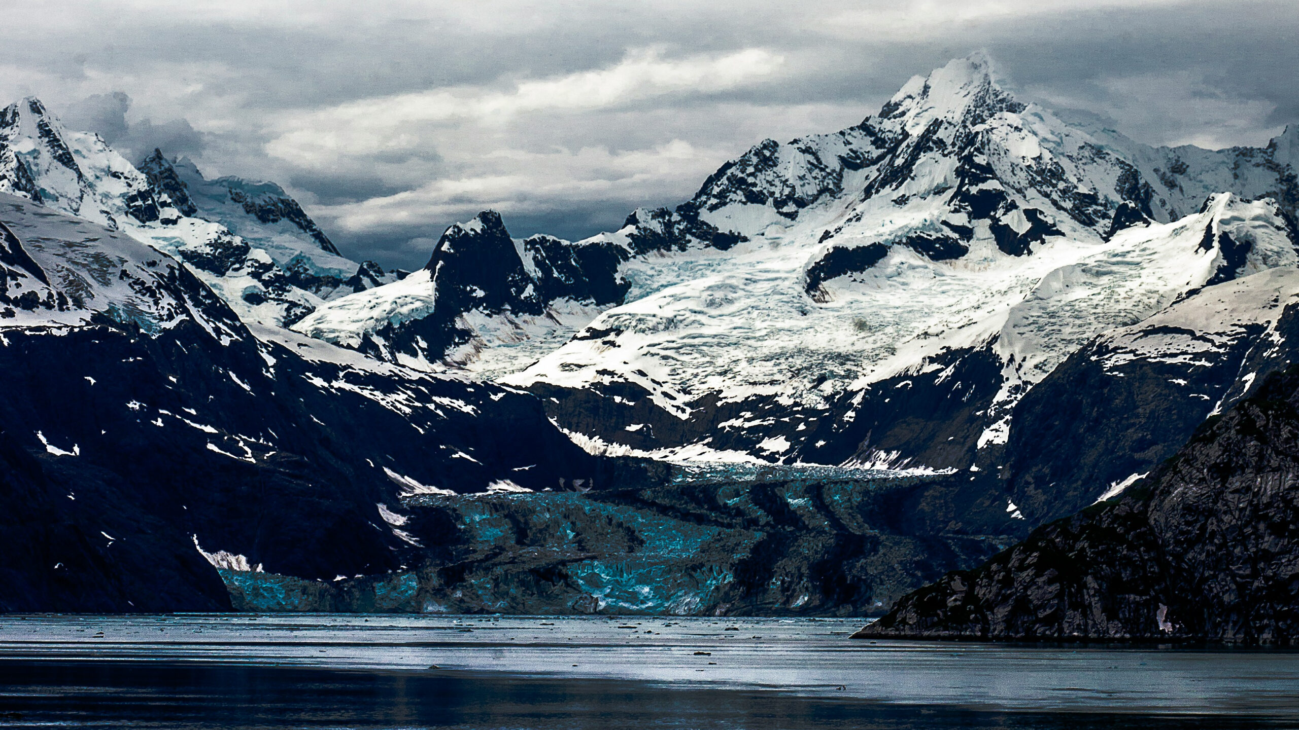 Snow capped mountains rise above a lake in Glacier Bay National Park