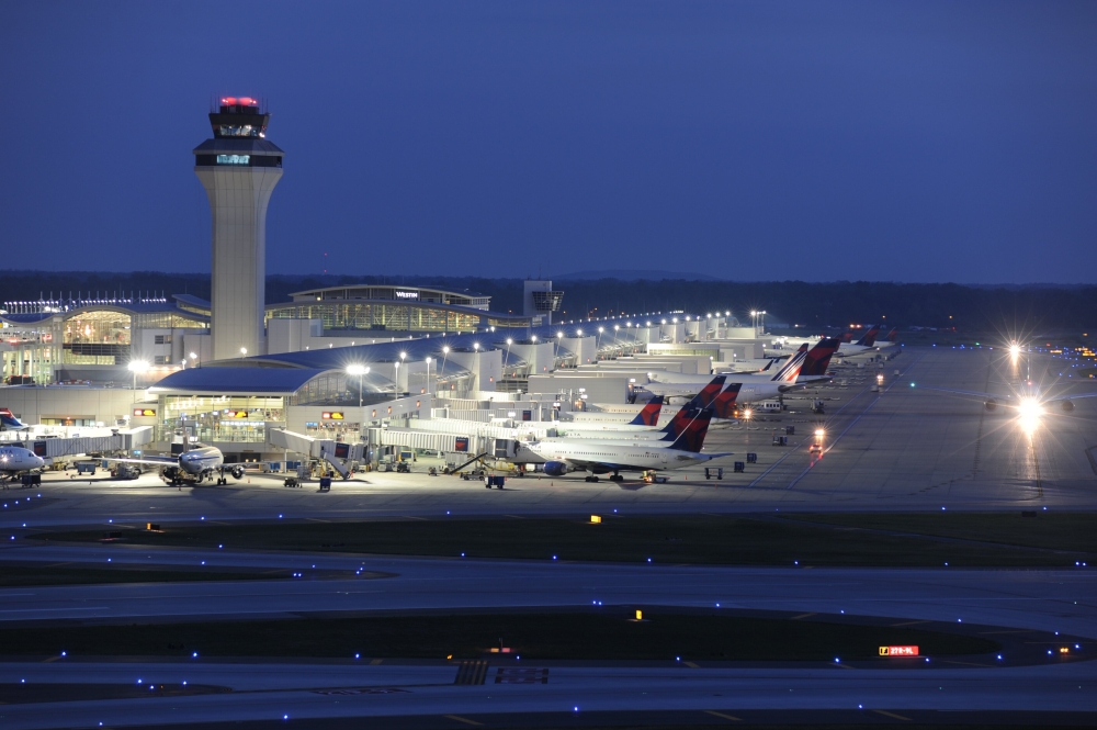 A nighttime aerial view of Detroit Metropolitan Wayne County Airport (DTW), with illuminated runways and terminal buildings.