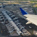 Aerial view from plane window displaying plane wing and airport terminal below.