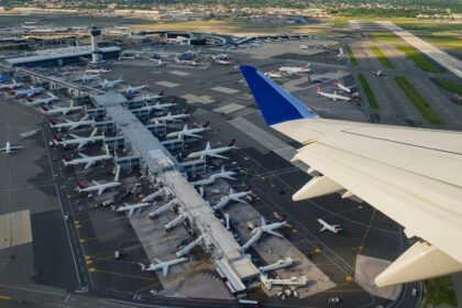Aerial view from plane window displaying plane wing and airport terminal below.