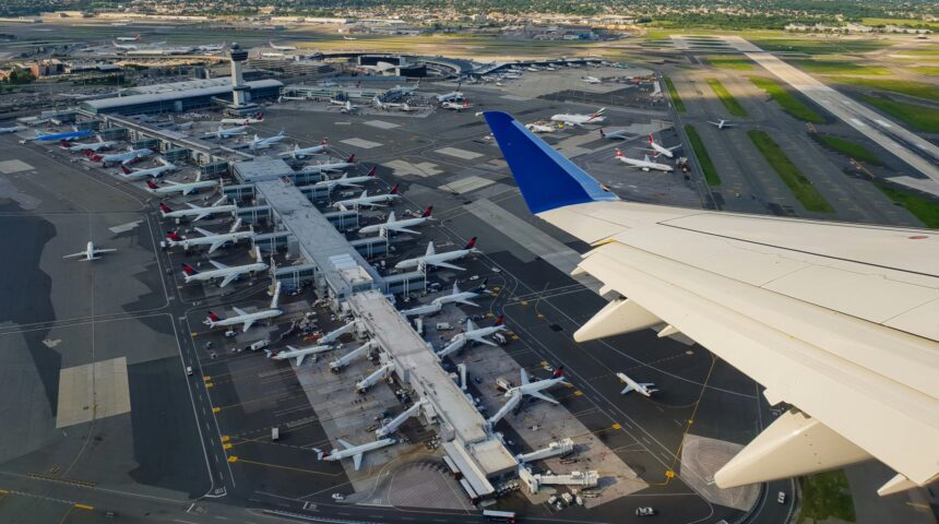 Aerial view from plane window displaying plane wing and airport terminal below.