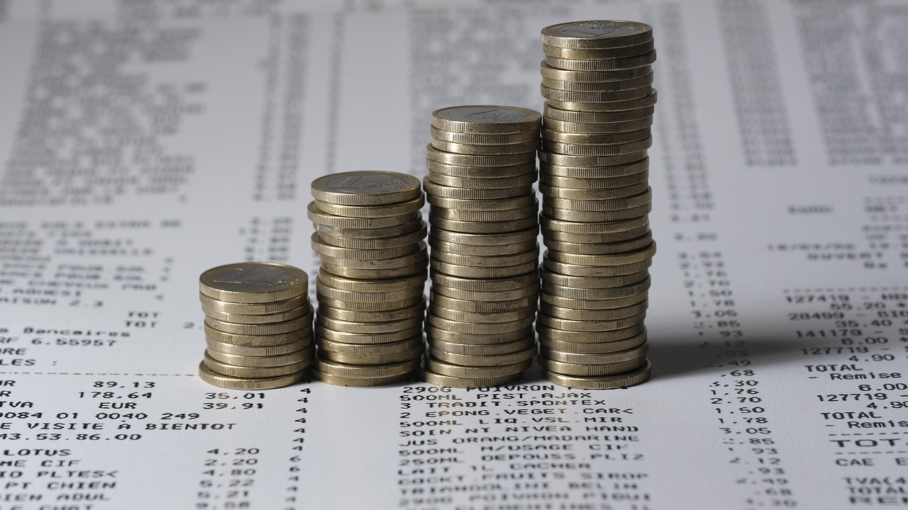 Stacks of coins on a financial report representing aviation emissions, sustainable aviation fuel costs and decarbonising aviation costs $5tn in the zero aviation transition.