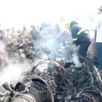 Onlookers view the smoke rising from the debris